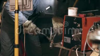 防护辉光男工在机械机库焊接两个金属件。